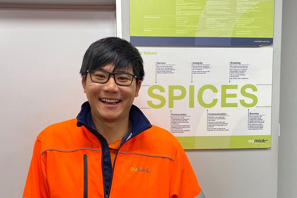 man in high vis jacket wearing glasses standing inside a warehouse