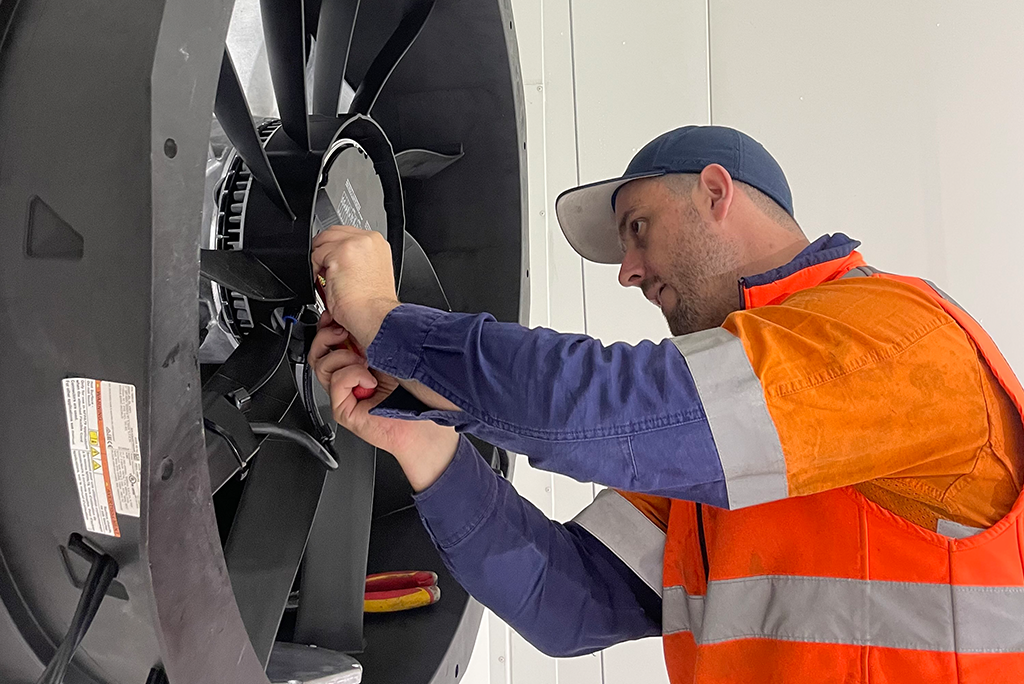 a person wearing high vis working on an industrial refrigeration fan