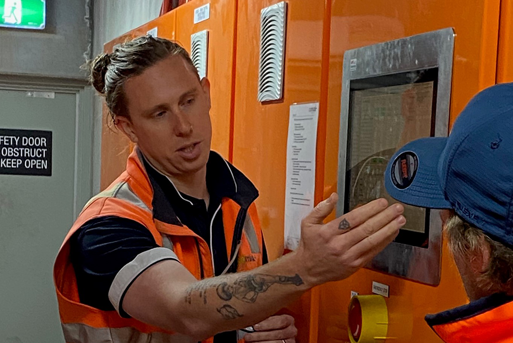 two men wearing high vis workwear and looking at a computer screen