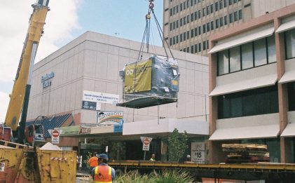 absorption chiller on a crane being carried over a building